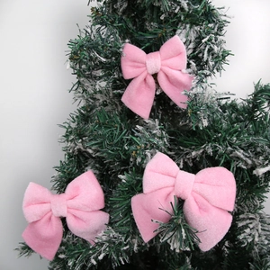 Detailed close-up of soft pink velvet Christmas bows on snowy green pine branches