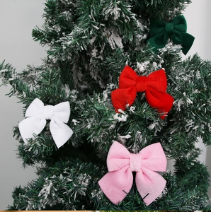 Velvet Christmas bows in red, pink, white, and green on a snowy tree branch detail