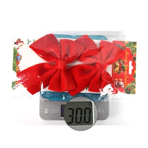 Detail shot of two red velvet Christmas bows showing 30g weight on a digital scale