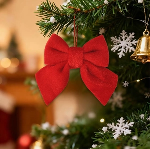 Close-up of a red velvet Christmas bow hanging on a tree branch with festive gold bells