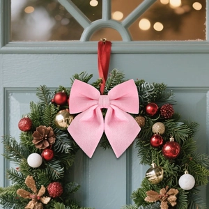 Close-up of a large pink velvet bow decoration on a classic Christmas wreath on a door