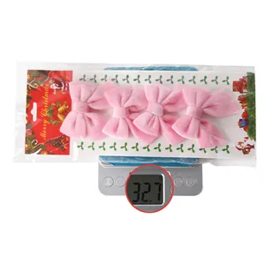 Detail showing weight of four pink velvet Christmas bows in package on digital scale