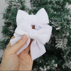 Close-up of a pair of white velvet bows held against a snowy Christmas tree background
