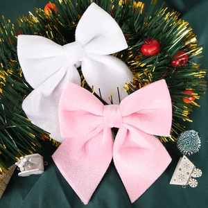 Close-up of white and pink velvet Christmas bows placed on a festive green wreath
