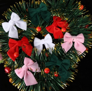 Close-up of velvet Christmas bows in red, white, green, and pink on a festive wreath