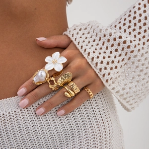 Gouden ringenset voor dames met bloemen, parels en onregelmatige texturen aan de hand