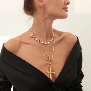 Gedetailleerd beeld van gelaagde ketting met parels, edelstenen en kruis hangers