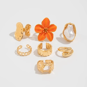Detail van de 7-delige gouden ringenset met barokparel en oranje bloemmotieven