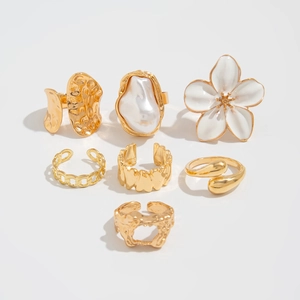 Gedetailleerde set van 7 goudkleurige ringen met barokparels en witte bloemdesigns