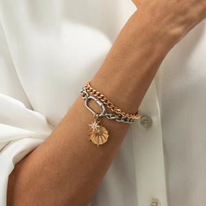 Detail of layered gold and silver chain bracelet featuring sun pendants and lobster clasp