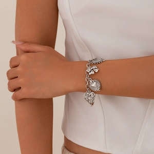 Silver charm bracelet with hollow hearts and bowknot charms worn on a female wrist