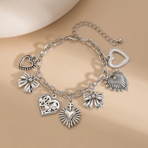 Detail of silver vintage bracelet featuring heart and bow charms on a chunky metal chain