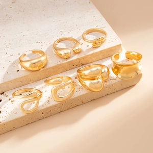 Set of seven golden abstract lava rings displayed on beige stone steps for a modern look