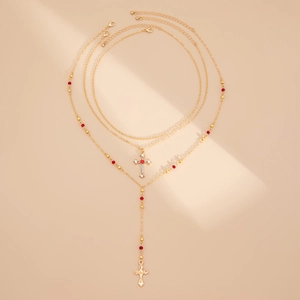 Détails d'un ensemble de 3 colliers dorés avec croix, perles rouges et cristaux brillants