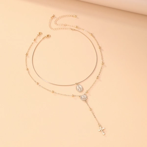 Détail du collier religieux doré à plusieurs rangs avec pendentifs Marie et croix
