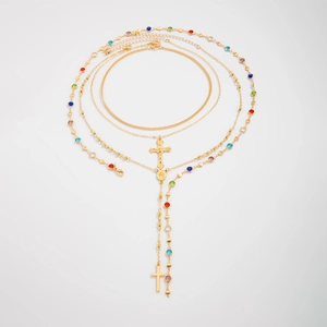 Vue détaillée de colliers triples dorés avec croix et perles de cristal colorées
