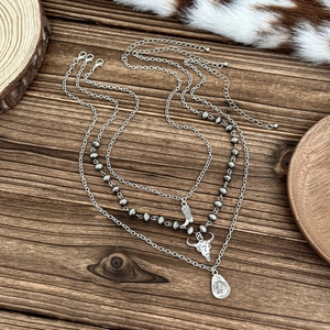 Detail of vintage silver necklace featuring western cowboy boot, skull, and hat pendants