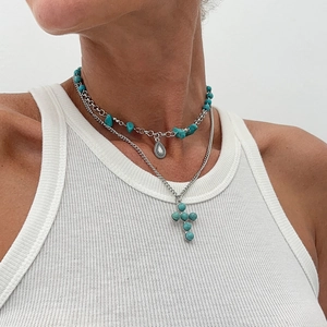 Detail of layered turquoise cross heart necklace on model with bohemian silver chains