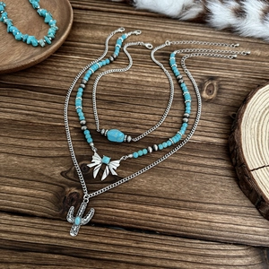 Close-up of bohemian layered silver necklace with turquoise beads and cactus pendant