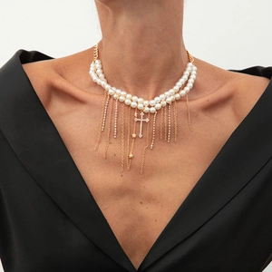 Details einer mehrlagigen Perlenhalskette mit Goldquasten und Kreuzanhänger an Model