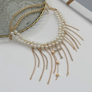 Detail der Perlenkette mit Strass-Kreuzanhänger und goldenen Quasten-Elementen