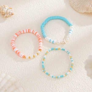 Three-piece ocean style bracelet set with starfish charms and colorful pearls on beach sand