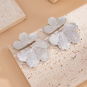 Dettaglio macro di orecchini a petalo argento con trame radiali metalliche rifinite