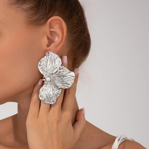 Orecchini a fiore d'argento oversize con perla centrale su modella per un look audace
