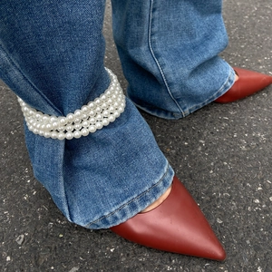 Chaîne de cheville à trois couches en perles d'imitation sur un jean bleu denim