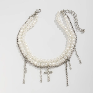 Detail of layered pearl anklet with rhinestone cross and silver fringe tassels