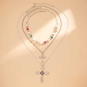 Detail van drielaagse ketting met kruishanger, parels en kleurrijke edelstenen accenten