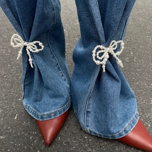 Classic white faux pearl bow clip accessory on blue jeans with stylish pointed red shoes