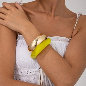 Close-up of vibrant neon yellow resin bangle paired with a gold-tone metallic bracelet