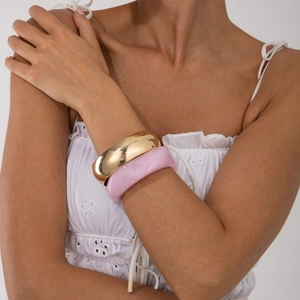 Close-up of polished gold metal bangle and pink marble resin bracelet set for women