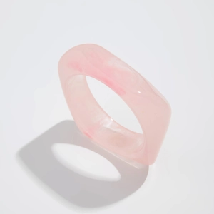 Macro shot of smooth square resin ring with pink marble texture and minimalist design