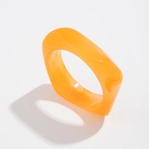 Detail shot of a modern translucent orange resin ring with irregular square edges
