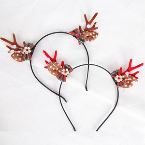 Close-up of reindeer antler headbands with plaid bows and daisy flowers for Christmas