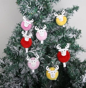 Close-up of colorful plush reindeer clips on snowy Christmas tree branches for decor