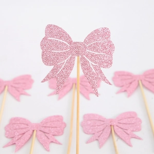 Detailed view of pink glitter bow cake topper on a wooden stick for party dessert decor