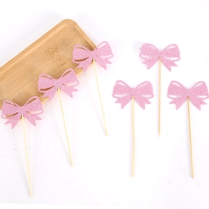 Detailed view of pink glitter bow cupcake toppers with wooden sticks for party decoration