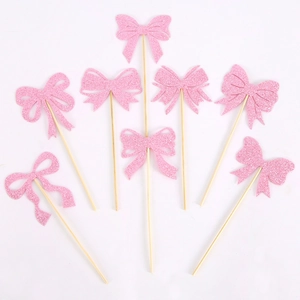 Close-up of pink glitter bow cake toppers with wooden sticks for party decorations