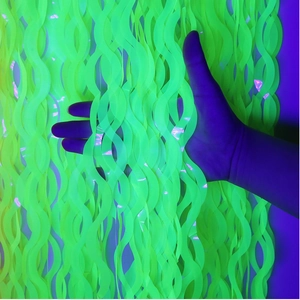 Dettaglio della tenda a frange ondulate verde neon che brilla sotto la luce UV party