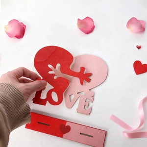 Kreatives LOVE Holzpuzzle-Ornament mit ineinandergreifenden Herzarmen auf Basis