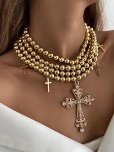 Détail d'un collier multicouche doré à perles avec pendentifs croix en cristal style hip hop
