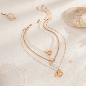 Détail du collier multicouche océan avec perles baroques et pendentifs coquillages dorés