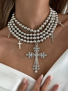 Détail d'un collier à perles argentées multicouches avec grand pendentif croix serti