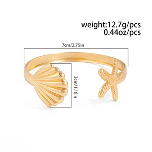 Detail shot of a polished gold starfish and shell open cuff bracelet with dimensions