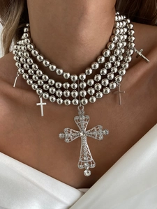 Détail de colliers multicouches en perles argentées avec pendentifs croix en zircon