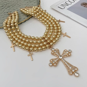 Détail du collier multicouche à billes dorées avec pendentifs croix en strass brillants
