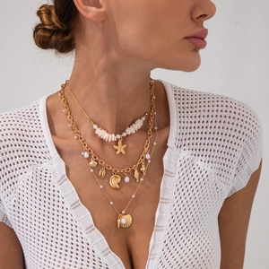 Détail d'un collier doré à plusieurs rangs avec pendentifs étoile de mer et perles